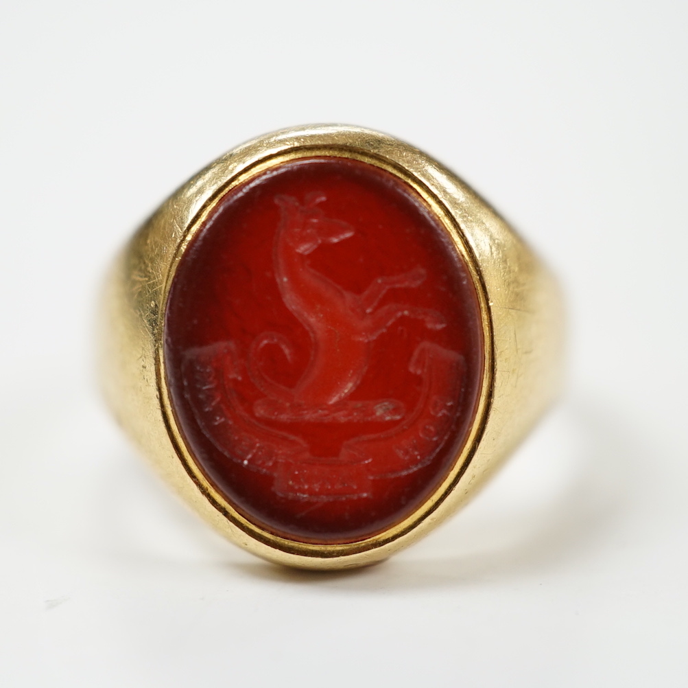 An 18ct and oval intaglio carnelian set signet ring, carved with family crest and motto, size K, gross weight 6.9 grams.